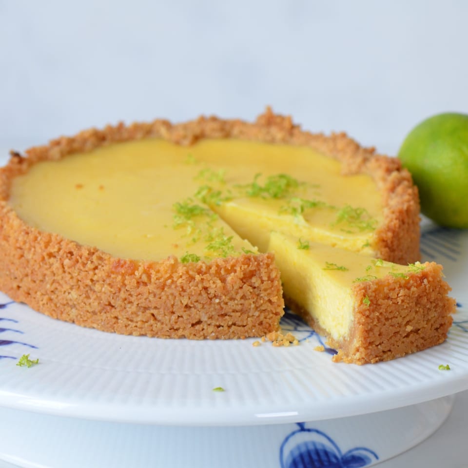 A Newman's Pour and Pies Key lime pie with a slice removed, garnished with lime zest.